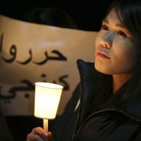 A woman in Tokyo holds a candle outside the prime minister\'s office during a rally for Kenji Goto on Wednesday. | AP
