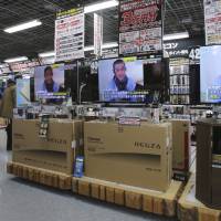 A sales clerk walks by TV sets broadcasting news about detained hostage Kenji Goto at an electronics store in Tokyo on Friday. The ransom deadline for two Japanese hostages held by the Islamic State group presumably passed on Friday. | AP