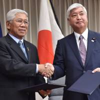 Defense Minister Gen Nakatani (right) and Philippine Defense Secretary Voltaire Gazmin exchange documents on their bilateral defense cooperation during a signing ceremony at the Defense Ministry in Tokyo on Thursday. Gazmin is on a three-day visit to Japan. | AFP-JIJI