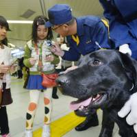 A police officer distributes canine calling cards to children in Tokyo in December. | KYODO