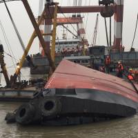 Rescuers on Friday climb on the tugboat\'s upturned hull. There was no word why the vessel sank. | CNSPHOTO/KYODO