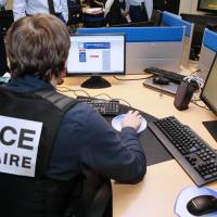 French police work at the headquarters of the Pharos cybercrime reporting platform on Monday in Nanterre, near Paris. Japanese officials announced Thursday that Japan will host a cybersecurity conference with the World Economic Forum in Okinawa this fall. | AFP-JIJI