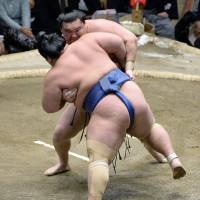 Face-to-face: Hakuho (rear) grapples with Kotoshogiku during the New Year Grand Sumo Tournament on Thursday. | KYODO