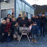 Broken but together: A photo outside Cafe De Monk in Minamisanriku\'s temporary-housing community after the 3/11 disaster. Mockett\'s son Ewan stands in front of various people in Mockett\'s book, \"Where the Dead Pause, and the Japanese say Goodbye.\" Mockett herself is at the back on the far left, standing behind her mother. | MARIE MUTSUKI MOCKETT