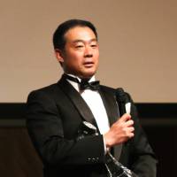 Prestigious honor: Yuichiro Fujita, head coach for the Higashi Fukuoka High School rugby team, receives the best coach award from presenter and former soccer player Nobutoshi Kaneda at the Japan Coaches\' Awards on Jan. 23 in Tokyo. | KAZ NAGATSUKA