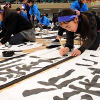 Calligraphers concentrate on their \"kakizome\" (New Year\'s writing) during an annual contest at the Nippon Budokan hall in Tokyo on Monday. Each peer group writes the same phrase, with their efforts judged on such factors as neatness. A total of 3,150 competitors from across the nation who won preliminary rounds took part in Monday\'s event. The winning works will be exhibited at the hall on Feb. 22. | SATOKO KAWASAKI