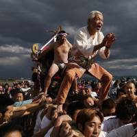 Men ride a \"mikoshi,\" or portable shrine, as residents carry it into the sea during a festival to wish for calm ocean waters and good fortune in the new year in Oiso, Kanagawa Prefecture, on Thursday. | REUTERS