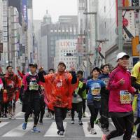 Participants run through the Ginza shopping district during the 2015 Tokyo Marathon on Sunday. | AP