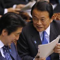 Deputy Prime Minister and Finance Minister Taro Aso speaks to Prime Minister Shinzo Abe during an Upper House committee session at the Diet in Tokyo on Feb. 3. | REUTERS