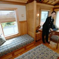 A Kyushu Railway Co. attendant shows off a deluxe suite aboard the luxury Seven Stars train in this image from 2013. The government said Friday it would fully privatize JR Kyushu in fiscal 2016, as its businesses are in good health. | KYODO