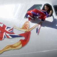 A flight attendant on Virgin Atlantic Airways\' last flight between Narita and Heathrow airports waves a Union Jack from the cockpit as it leaves Japan on Sunday. The British airline has halted Narita-London flights as it revises its international routes. | KYODO