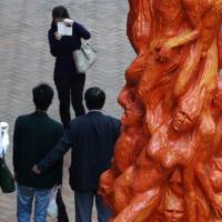 Visitors at the University of Hong Kong pose Tuesday in front of the \"Pillar of Shame\" sculpture mourning those who died during the June 4, 1989, military crackdown on the pro-democracy movement in Beijing\'s Tiananmen Square. | REUTERS
