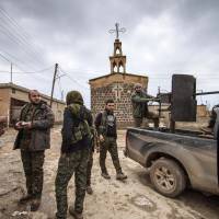 Fighters from the Kurdish People\'s Protection Units (YPG) stand near a pickup truck mounted with an anti-aircraft weapon in front of a church in the Assyrian village of Tel Jumaa, north of Tel Tamr town, on Feb. 25, 2015. Kurdish militia launched an offensive against the Islamic State group in northeast Syria on Wednesday, cutting one of its supply lines from Iraq, as fears mounted for dozens of Christians abducted by the jihadi group. | REUTERS