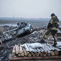 A pro-Russian rebel guards a captured former Ukrainian Army checkpoint outside Vuhlehirsk in the Donetsk region in eastern Ukraine on Thursday. | AP