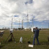 Members of the media set up remote cameras in front of the unmanned Falcon 9 rocket set to be launched by SpaceX carrying NOAA\'s Deep Space Climate Observatory Satellite on launchpad 40 at the Cape Canaveral Air Force Station in Cape Canaveral, Florida, on Sunday. | REUTERS