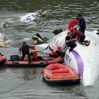 Rescue personnel work to free passengers from a TransAsia ATR 72-600 turboprop plane that crash-landed into a river outside Taiwan\'s capital Taipei in New Taipei City on Wednesday. The passenger plane with 58 people on board was on a domestic flight when it plunged into the river, with at least 10 people rescued and dozens trapped inside, according to television reports. | AFP-JIJI