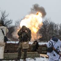 Russian-backed separatists cover their ears as they fire a mortar toward Ukrainian troops outside the village of Sanzharivka, northeast of Debaltseve in eastern Ukraine, on Wednesday. | AP