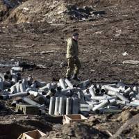 A fighter with the separatist self-proclaimed Donetsk People\'s Republic army looks for ammunition in a destroyed Ukrainian army compound in the town of Debaltseve on Sunday. | REUTERS