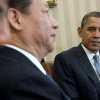 U.S. President Barack Obama and Chinese President Xi Jinping speak during a meeting in the Oval Office of the White House in Washington, DC, in February 2012. The U.S. president has called on China to help soothe a lingering conflict over cybersecurity amid mutual accusations of hacking and data theft. | AFP-JIJI