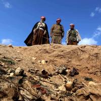 Members of the Yazidi sect peer into a mass grave in the northwestern Sinjar area of Iraq containing the remains of people slaughtered by Islamic State militants, as they search for clues that might lead them to missing relatives. | AFP-JIJI