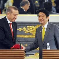 A file photo shows Prime Minister Shinzo Abe shaking hands with then Turkish Prime Minister Recep Tayyip Erdogan in Tokyo in January 2014. | KYODO