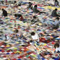 Residents and outside volunteers stitch together donated cloth squares to make a huge quilt in Ishinomaki, Miyagi Prefecture, last September. Guinness World Records has declared it the world\'s largest blanket. | KYODO