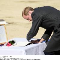 Prince William signs a visitors\' book at the Commonwealth War Cemetery in Yokohama on Friday, where he was shown a photograph of his late mother, Princess Diana, during a visit she made to the site. | KYODO