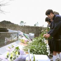 Students at Uwajima Fisheries High School in Ehime Prefecture lay flowers Tuesday at a memorial for the nine people who died in 2001 when a U.S. submarine surfaced beneath the school\'s training vessel. | KYODO