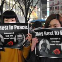 Sisters Shiori (left) and Nanami Katori mourn Kenji Goto and Haruna Yukawa, the two Japanese hostages killed by the Islamic State group, during an event at Hachiko square in Tokyo\'s Shibuya Ward on Sunday. | YOSHIAKI MIURA