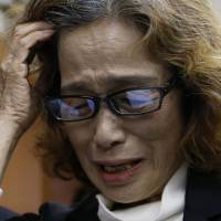 Junko Ishido, mother of slain journalist Kenji Goto, who was held captive by Islamic State militants, touches her head as she speaks to reporters at her Tokyo home Sunday. Islamic State militants said earlier they had beheaded Goto, the second Japanese hostage, after the failure of international efforts to secure his release through a prisoner swap. | REUTERS