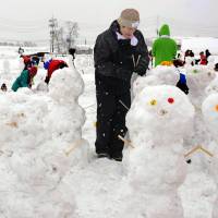 People in Iiyama, Nagano Prefecture, take part in attempt on Sunday to break the Guinness World Record for most snowmen made in one hour. The group of 630 people was successful in creating 1,583 snowmen within the time limit. | KYODO