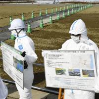Workers discuss planned interim facilities for contaminated soil in Futaba, Fukushima Prefecture, on Tuesday. | KYODO