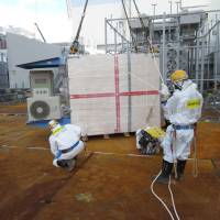 This handout picture taken by Tokyo Electric Power Co. on Monday shows a measuring device of cosmic rays, to be used to look inside crippled reactors, being installed at Tepco\'s Fukushima No. 1 nuclear plant at Okuma, Fukushima Prefecture. The device will use muons to check fuel debris inside the reactors. | AFP-JIJI/TEPCO