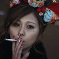 Small pleasures: A young woman takes a smoke break while celebrating Coming-of-Age Day at an amusement park last month. In violent times, young Japanese just shrug