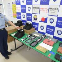 A customs officer displays fake products confiscated at Sakaiminato port in Tottori Prefecture last August. | KYODO