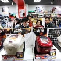Chinese tourists compare rice cookers at the Laox in Tokyo\'s Ginza district Feb. 16. | BLOOMBERG