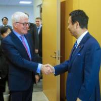 New Zealand Trade Minister Tim Groser and trade minister Akira Amari shake hands in Tokyo on Wednesday before talks. | KYODO