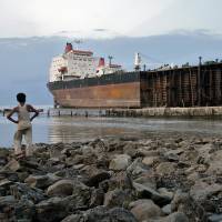 A young boy looks out at a tanker being scrapped at a Bangladeshi shipbreaking yard on April 29, 2005, near Chittagong. | BLOOMBERG