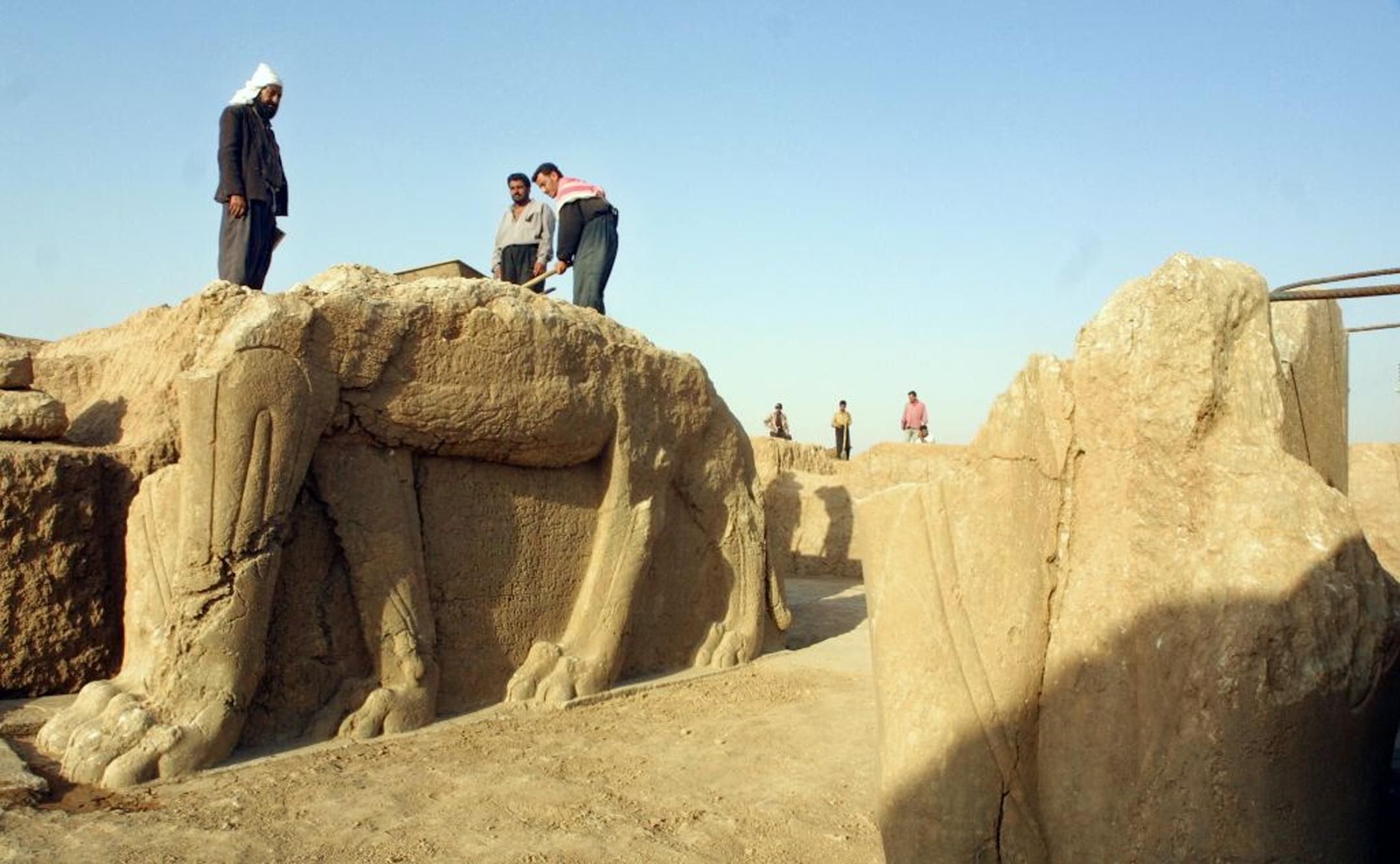 A file picture taken in 2001 shows Iraqi workers cleaning a statue of winged bull at an archeological site in Nimrud, 35 km southeast of the northern city of Mosul. The Islamic State group has begun bulldozing the ancient Assyrian city of Nimrud in the jihadis' latest attack on the country's historical heritage. Iraq is urging U.S.-led airstrikes to save the artifacts. | AFP-JIJI