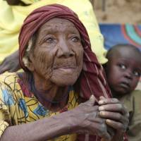 An elderly woman sits on the ground in the recently retaken town of Damasak, Nigeria, on Friday. Soldiers from Niger and Chad who liberated the Nigerian town of Damasak from Boko Haram militants have discovered the bodies of at least 70 people, many with their throats slit, scattered under a bridge. | REUTERS