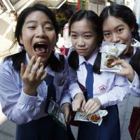 Schoolgirls eat HiSo snacks during a promotional event in Bangkok on Tuesday. | REUTERS