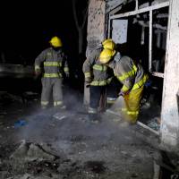 Afghan firefighters hose down the site of a suicide attack targeting lawmaker Gul Pacha Majidi, in Kabul on Sunday. The suicide attacker targeting the prominent Afghan MP killed three people and wounded seven others, just days after Washington announced it would slow the withdrawal of U.S. troops from Afghanistan. | AFP-JIJI