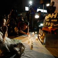 Kelly Wen, wife of a Chinese passenger who was aboard missing Malaysia Airlines Flight MH370, prays during an event to mark the one-year anniversary of the plane’s disappearance, during a candlelight vigil for passengers in Kuala Lumpur on Friday. As world turns, MH370 families find solace in each other