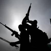 Fighters from the Saraya al-Salam (Peace Brigades), a group formed by Iraqi Shiite Muslim cleric Moqtada al-Sadr, wave their weapons as they leave the holy city of Najaf on Friday. They were traveling with government forces to the northern city of Tikrit, where the offensive against Islamic State group jihadis continues. | AFP-JIJI