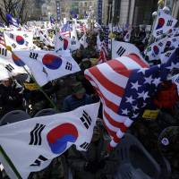 South Korean veterans hold South Korean and U.S. flags during a rally denouncing the attack on Mark Lippert, the U.S. ambassador to the country, in downtown Seoul on March 9. | AP