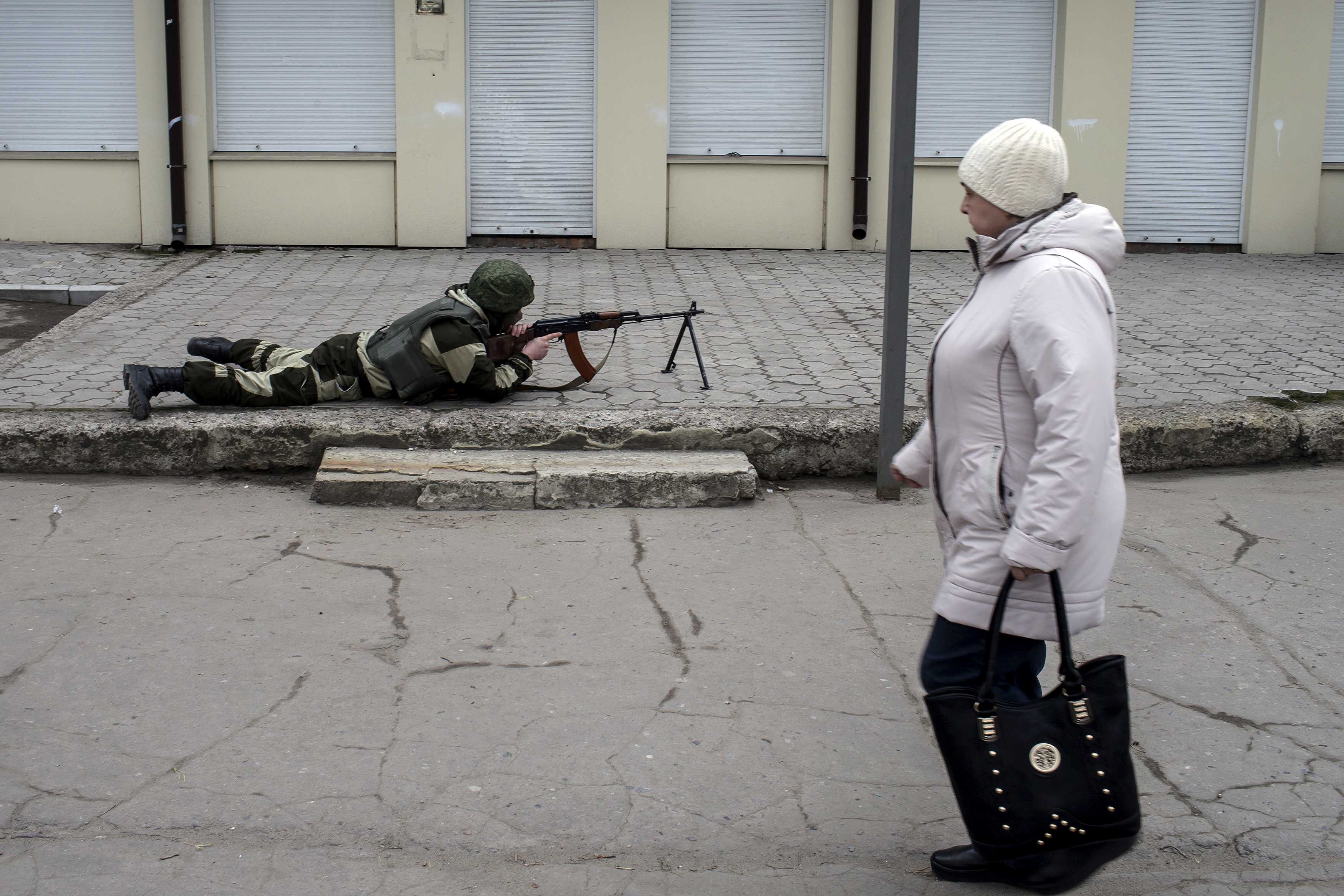 A pro-Russian rebel aims his weapon as a woman passes by during what the rebels said was an anti-terrorist drill in Donetsk, Ukraine, Wednesday. Rebel-held areas of east Ukraine are suffering deteriorating water supplies amid the continued strife. | REUTERS