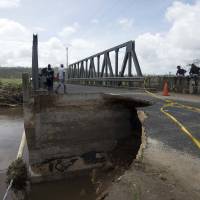 Local residents stand by a bridge near Port Vila, the capital of Vanuatu, on Sunday. Parts of the Pacific island nation were extensively damaged by Cyclone Pam at the end of last week. | REUTERS
