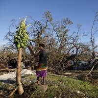 A girl picks fruit Tuesday from a tree in Lenakel town in Tanna, days after Cyclone Pam hit the South Pacific island nation of Vanuatu. International aid agencies began emergency flights on Tuesday to some of the remote outer islands of Vanuatu, which they fear have been devastated by the monster cyclone that tore through the nation. Disaster management officials and relief workers are still battling to get rescue teams on many of the islands that bore the brunt of Cyclone Pam. | REUTERS