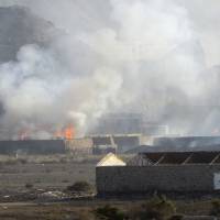 Buildings at the Jabal al-Hadid military camp burn as smoke rises in Aden on Saturday. Yemeni military officials said an explosion at the camp, which houses a weapons depot and had been taken by security forces loyal to ousted leader Ali Abdullah Saleh, killed several people. | AP