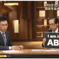 Shigeaki Koga (right), a former government bureaucrat critical of Prime Minister Shinzo Abe, holds up a sign in this screenshot of his appearance on a news program aired by TV Asahi on Friday. | JON MITCHELL